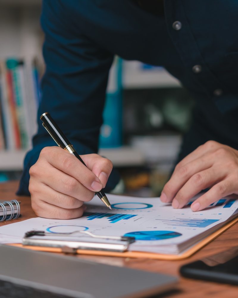 A business strategist pens insights on paper charts with analytics, fostering data-driven decisions.